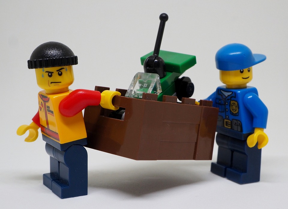Two Lego figures are carrying some lego bricks