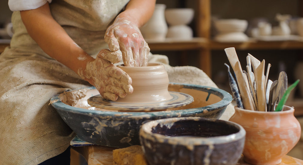 person making pottery on pottery wheel