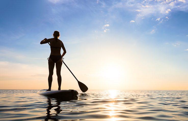 Woman paddleboarding at sunset
