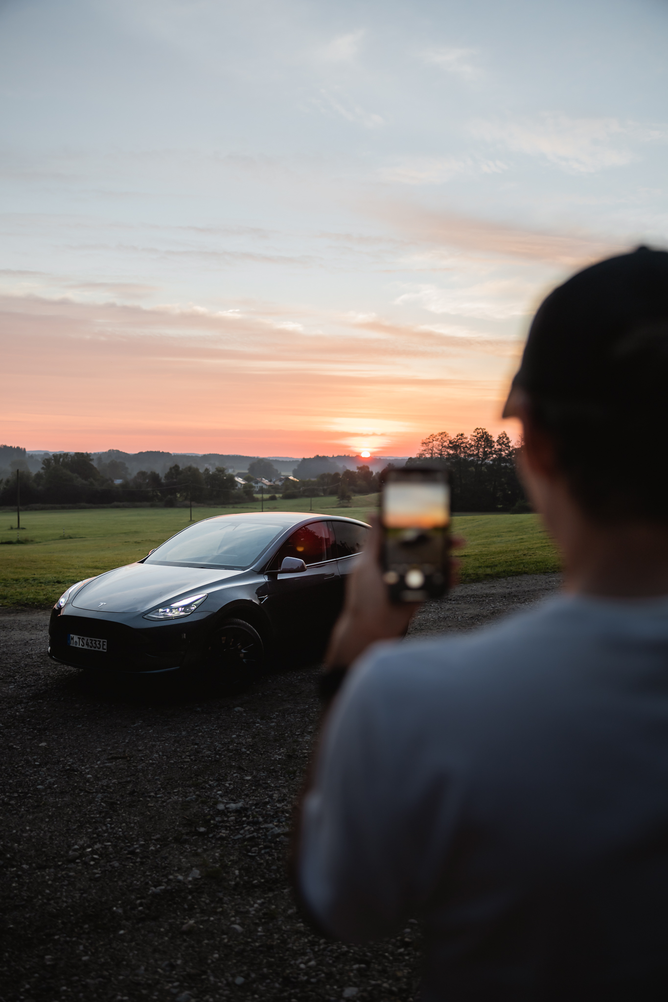 Man taking picture of Tesla during sunset.