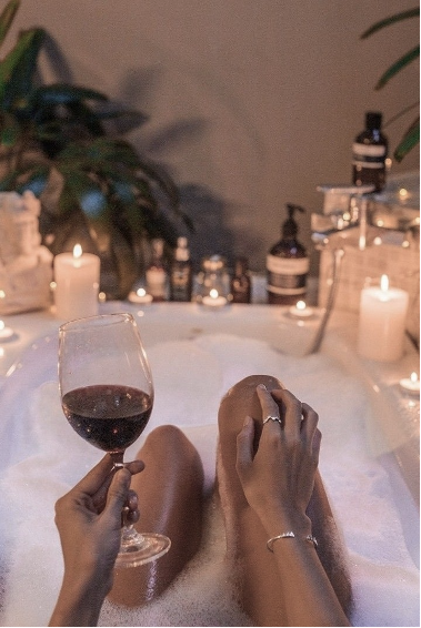 woman relaxing in a bath with wine