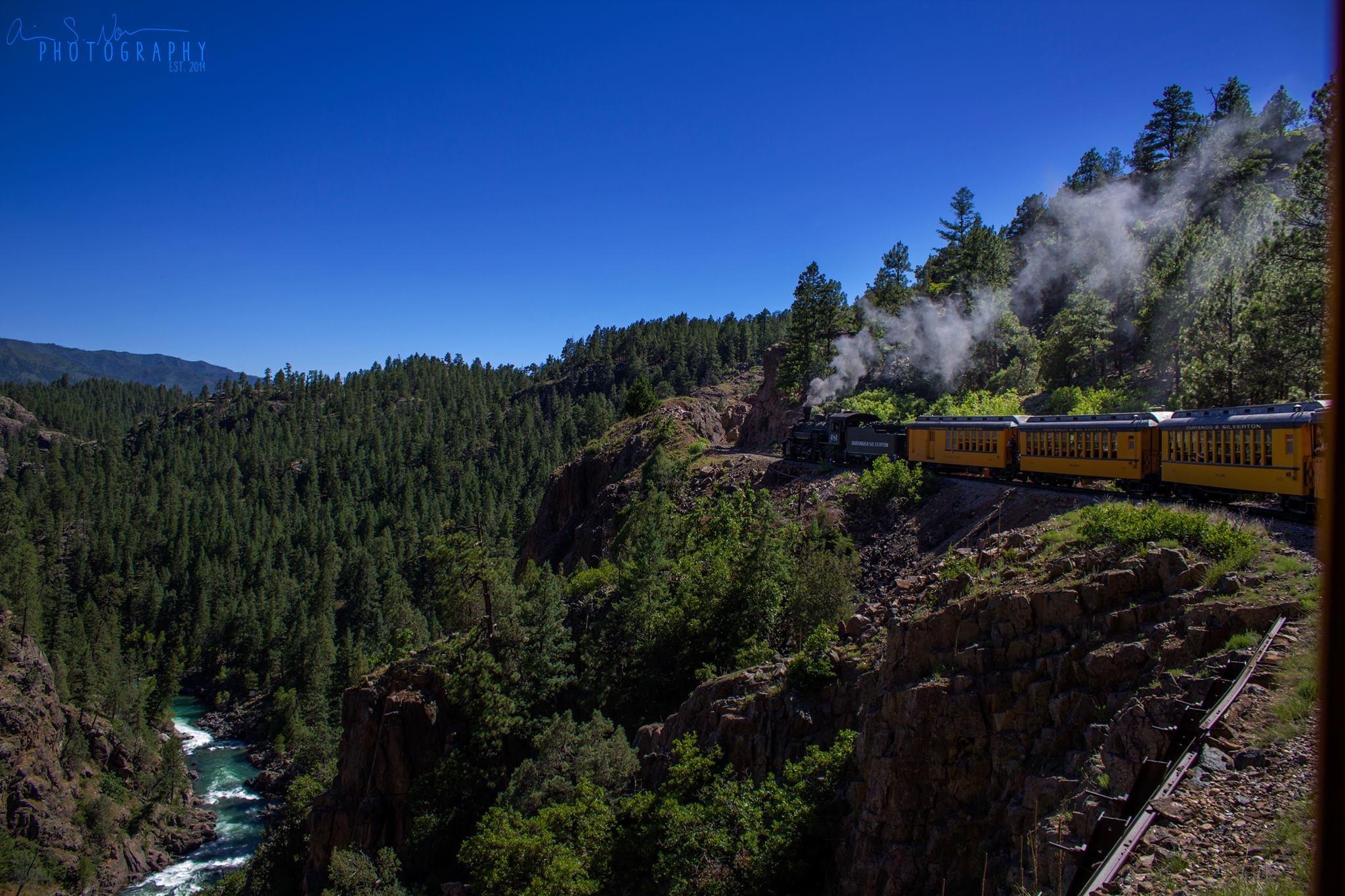 train in mountains with river below