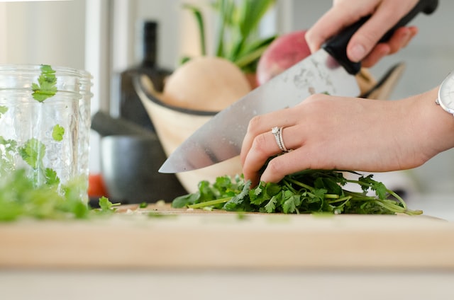 Hand holding a knife cutting herbs