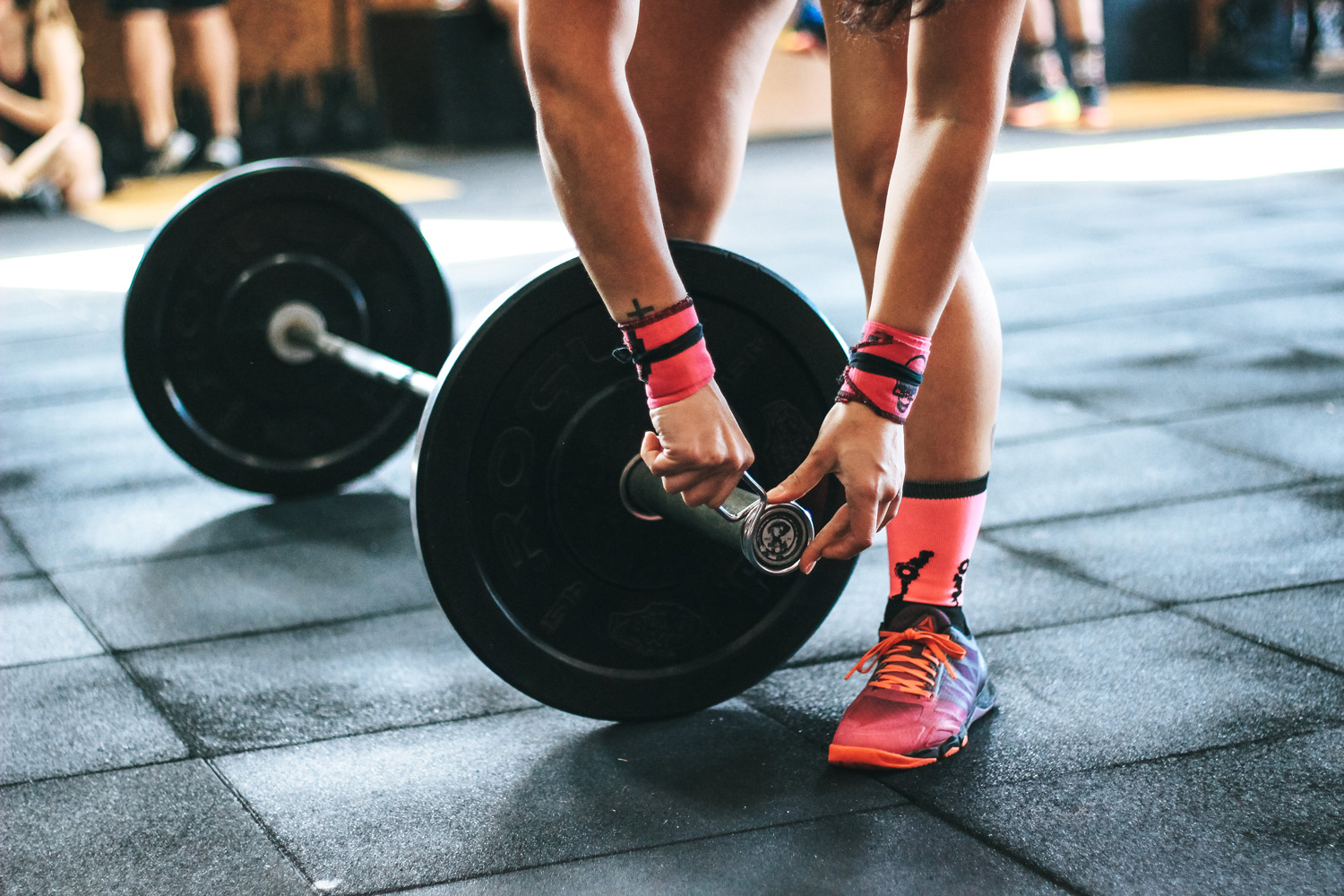 Close up of persons hands doing up clip on barbell