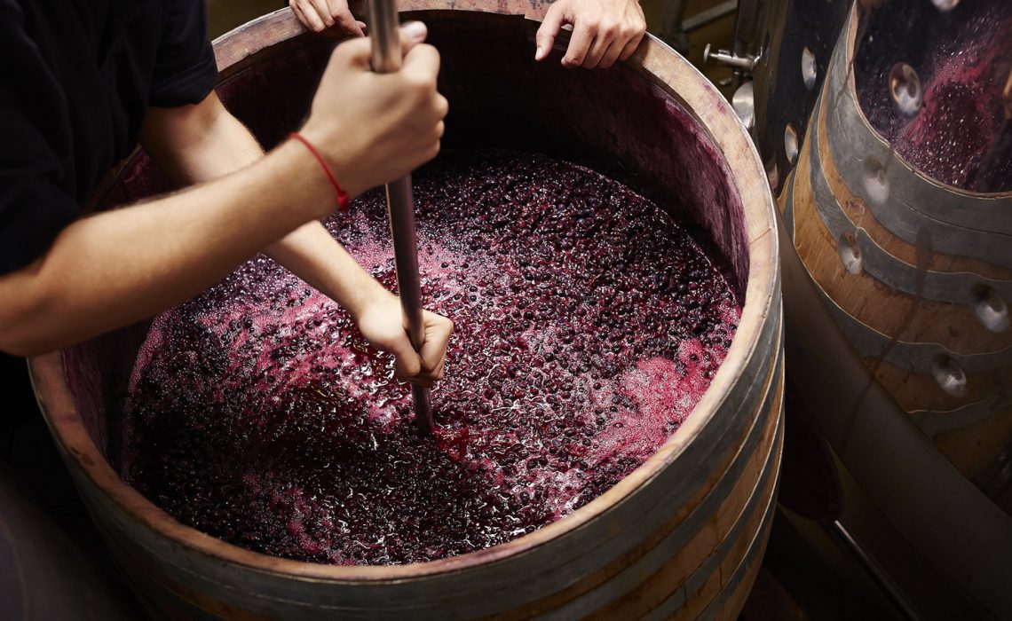 red wine fermenting in large wooden barrel