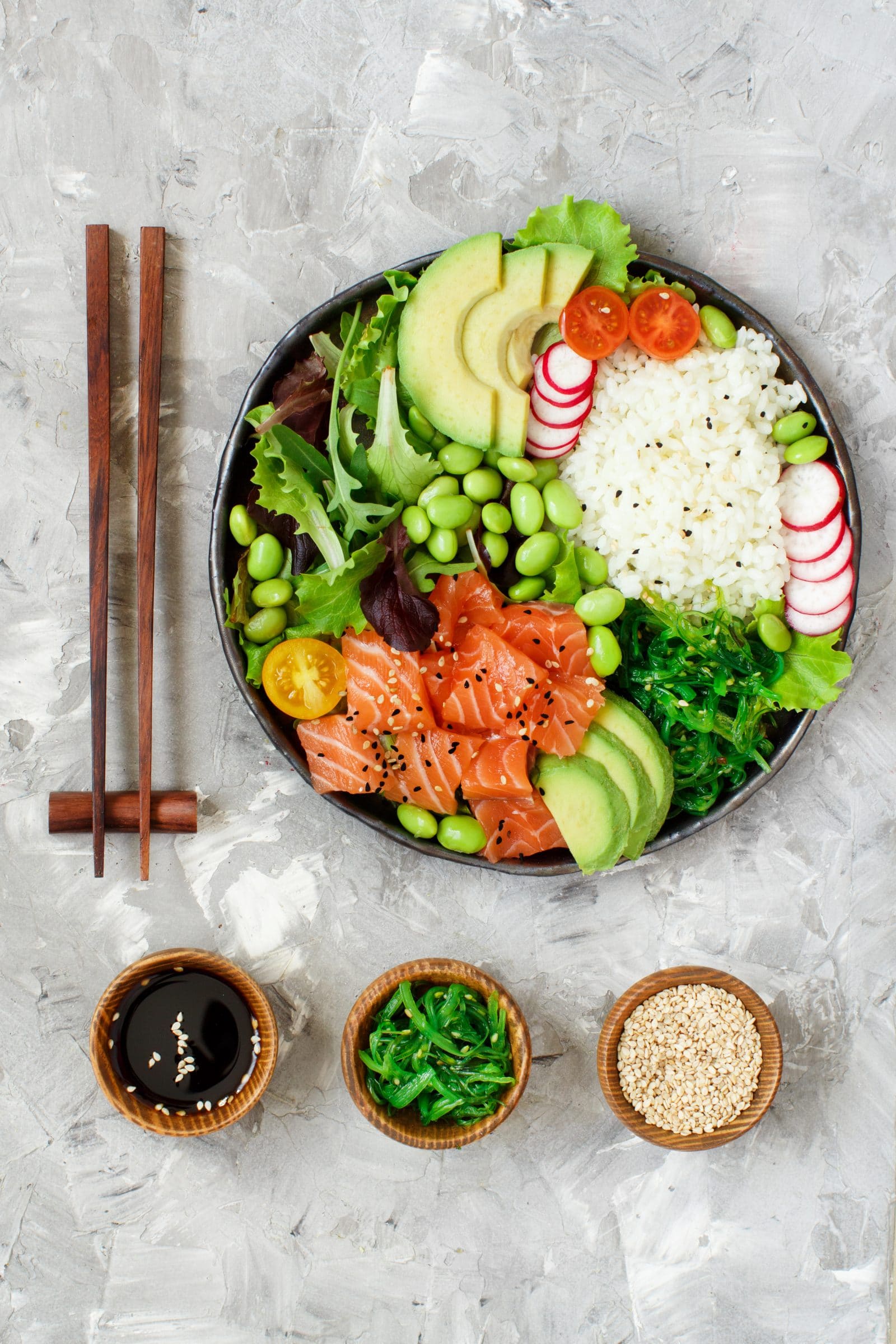 Poke bowl w/ rice, salmon, avocado, seaweed salad, sauces, & chopsticks