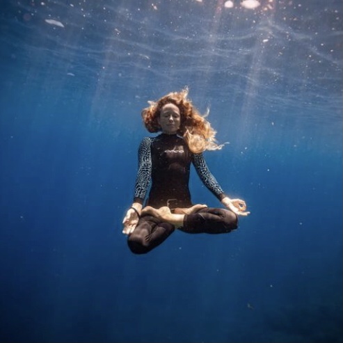 Woman in meditative pose under water