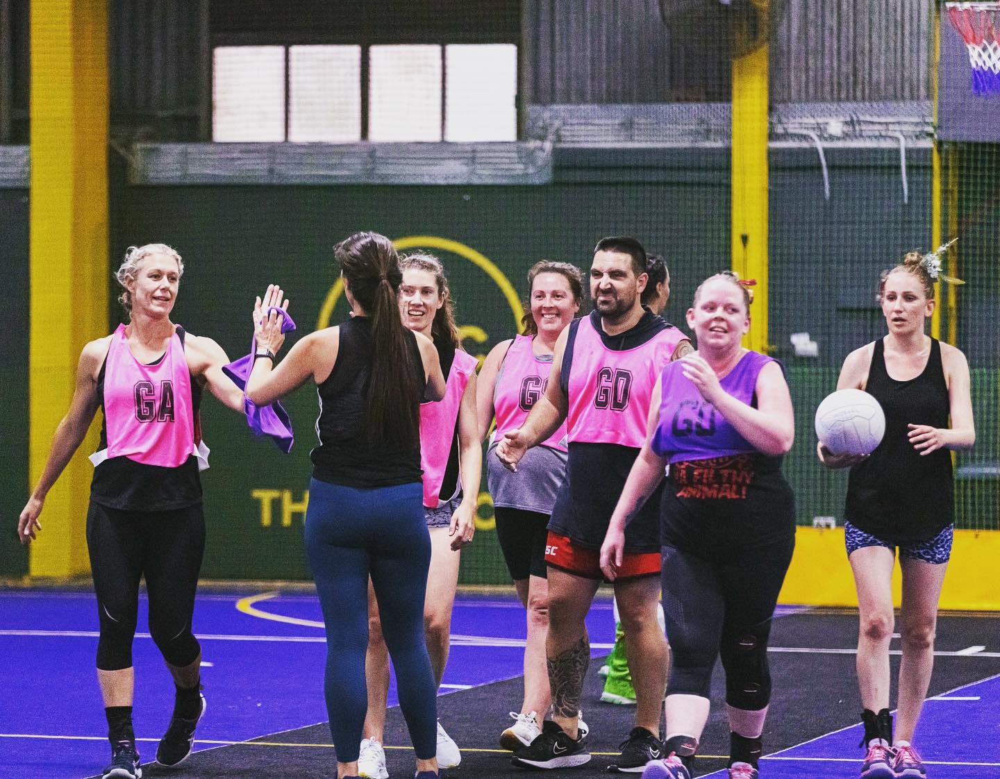 Netball players indoor high fiving on court