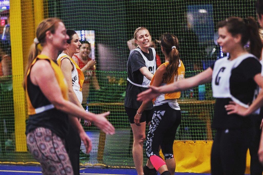 Netball players indoor shaking hands on court