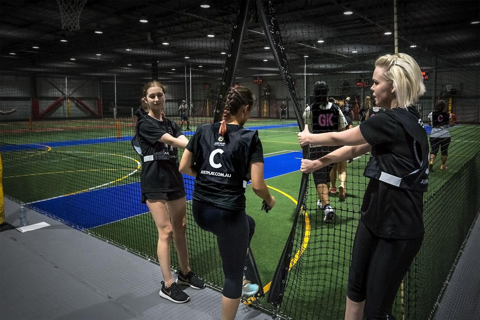 Netball players indoor holding netting door open