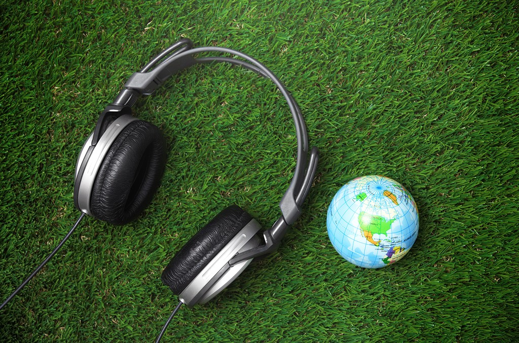 photo of headphones with world on a bed of grass