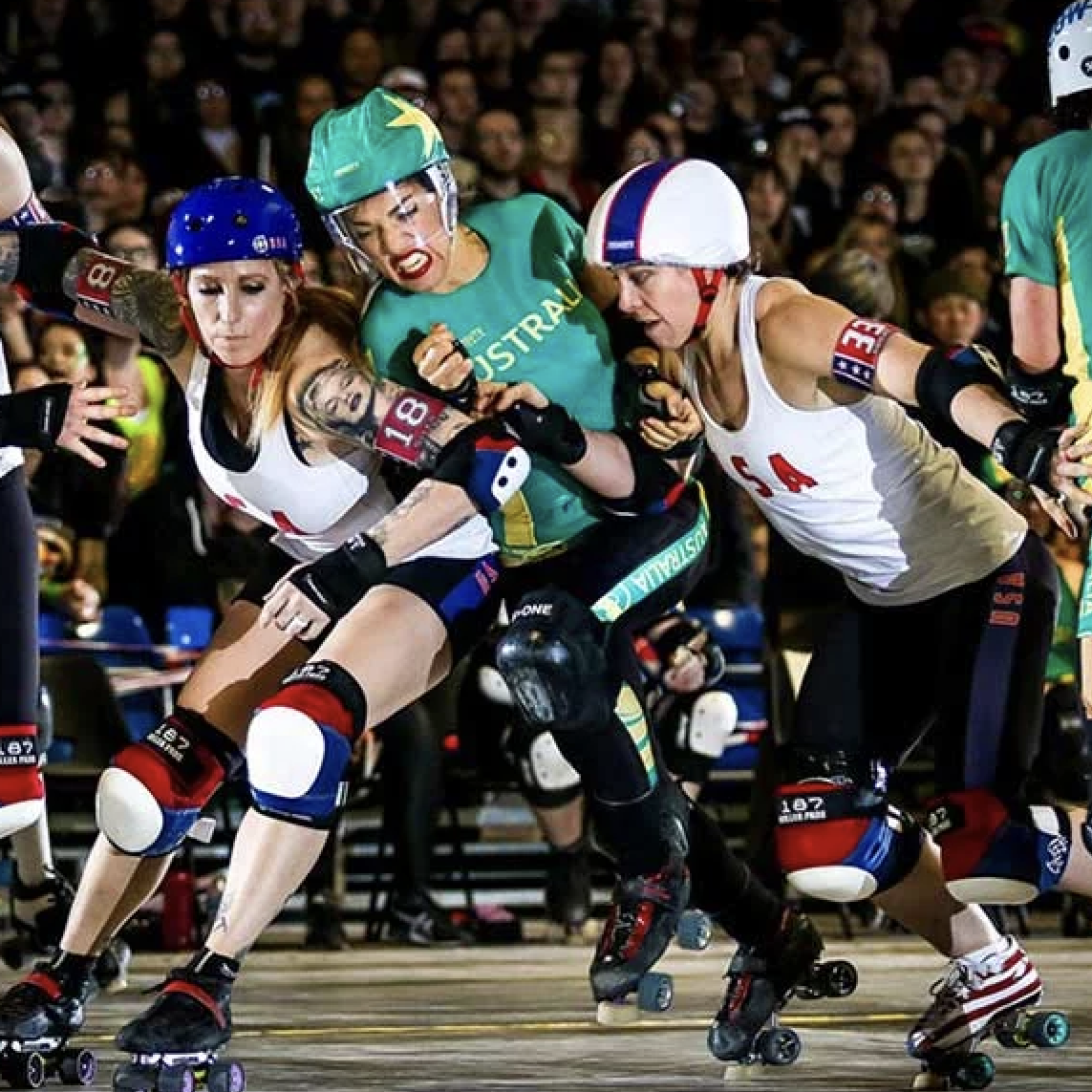 A group of skaters jostle for position in a roller derby game