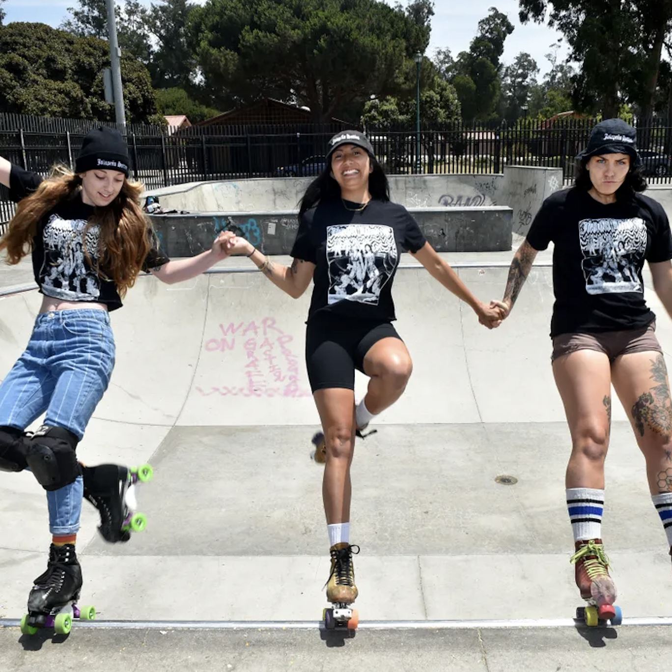 Three roller skaters on the lip of a ramp join hands