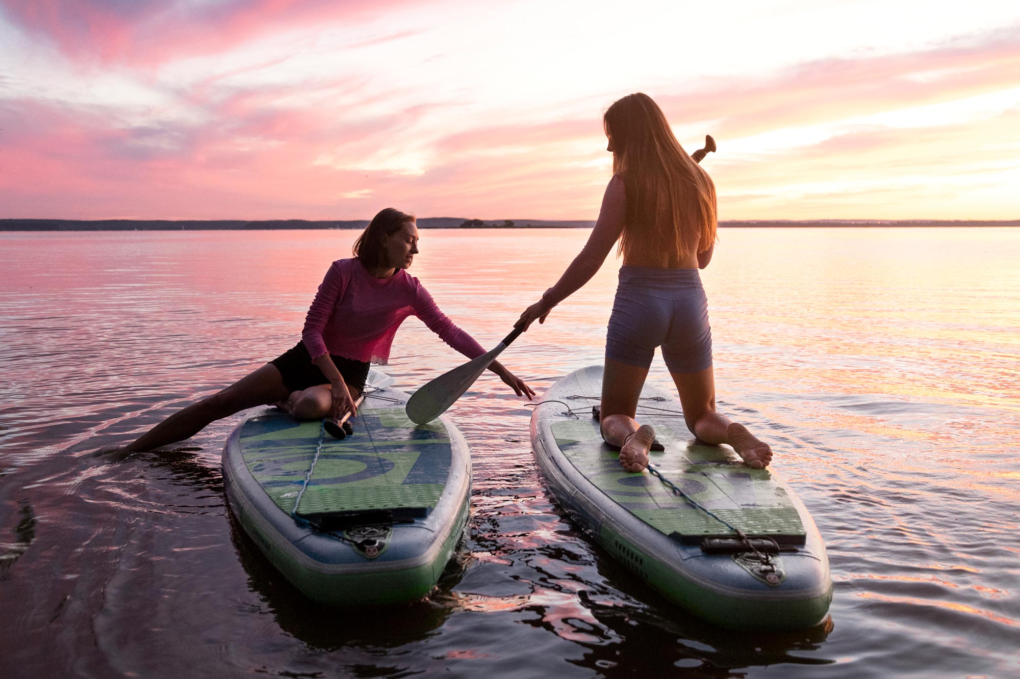 Two women standup paddling during sunset