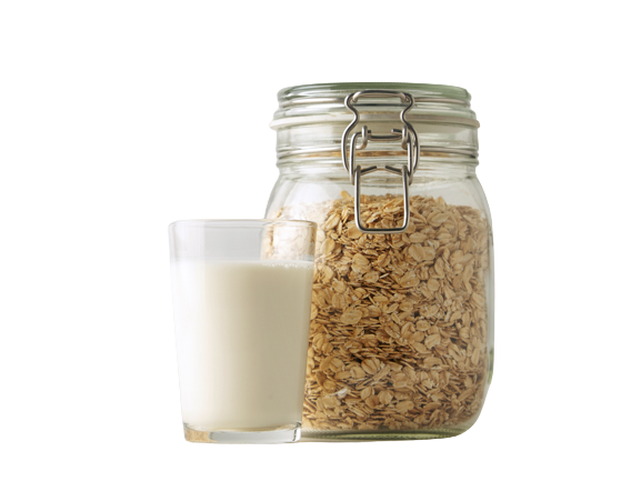 A glass of oatmilk with a storage container of oats next to it