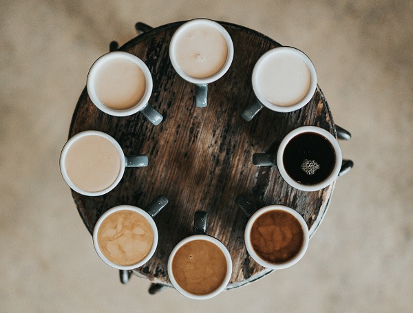 a collection of coffees organised in a circle on a wooden tray
