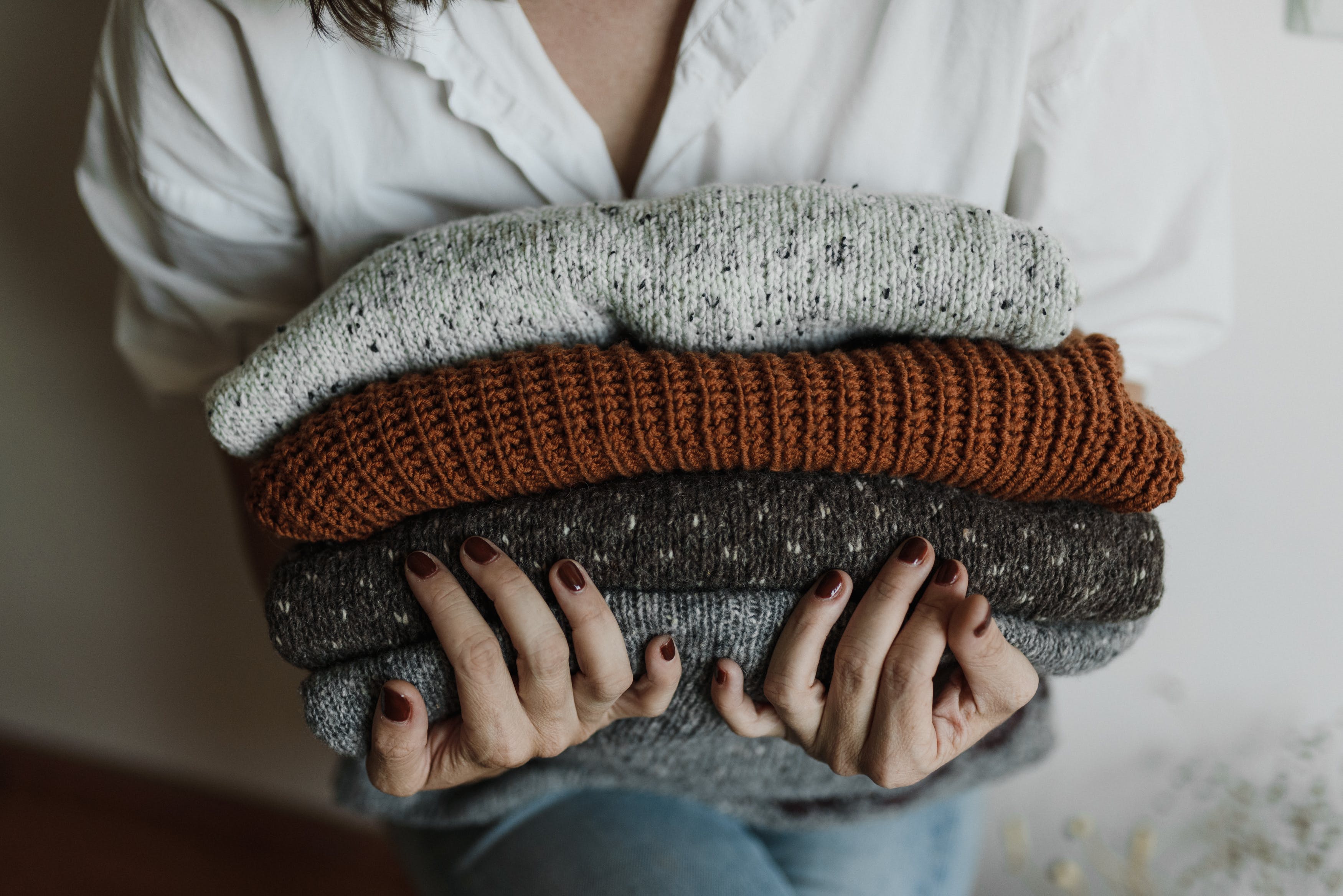 Woman holding a stack of sweaters
