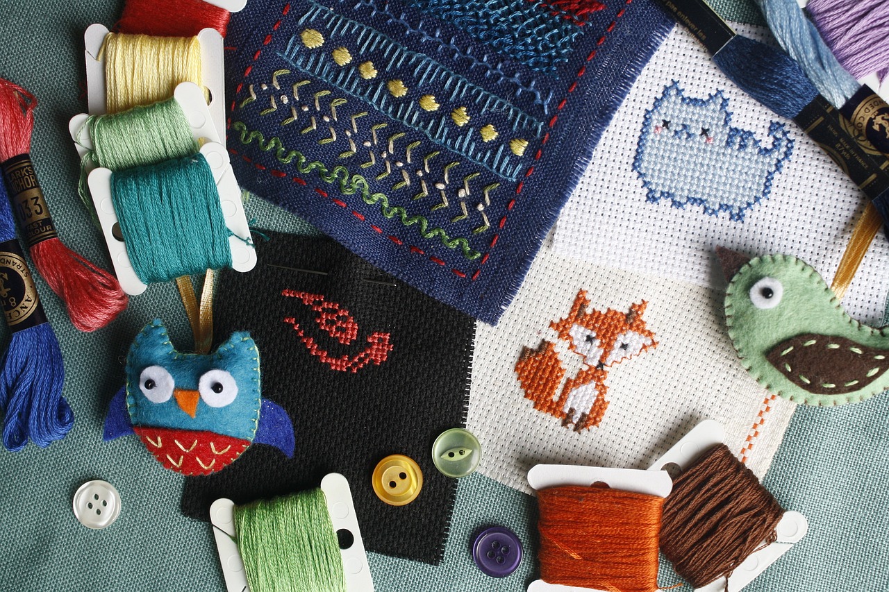 a mixed assortment of embroidment items: different coloured threads, needles, buttons, a 2D embroided fox, a cute 2D embroided cartoon cat on thick canvas; and asorted related items. 