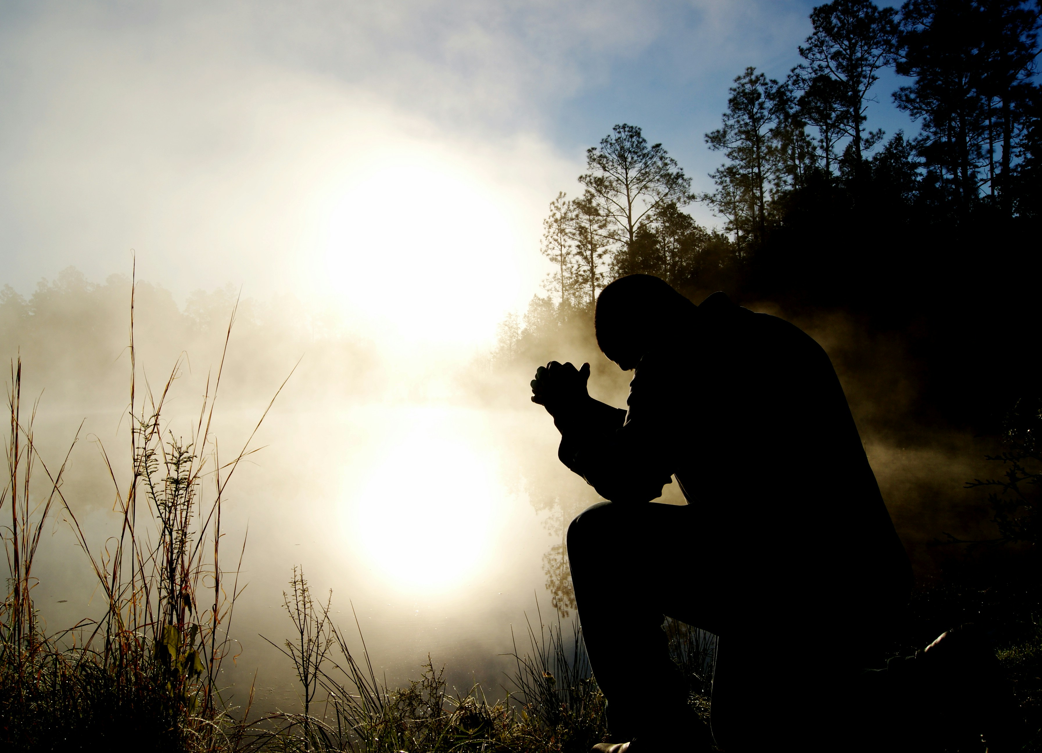 man praying outside in foggy field