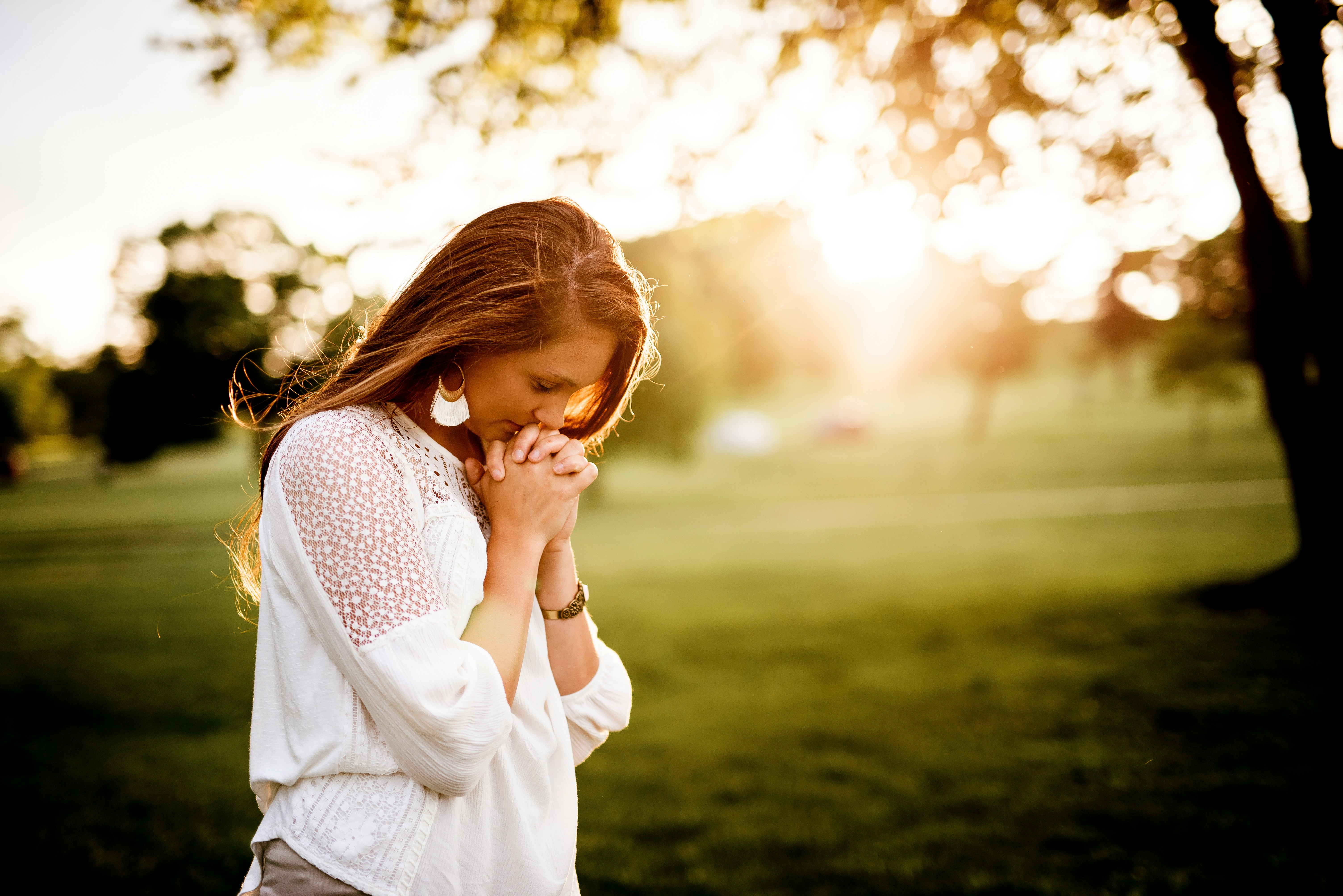 woman walking and praying outside on a sunny day