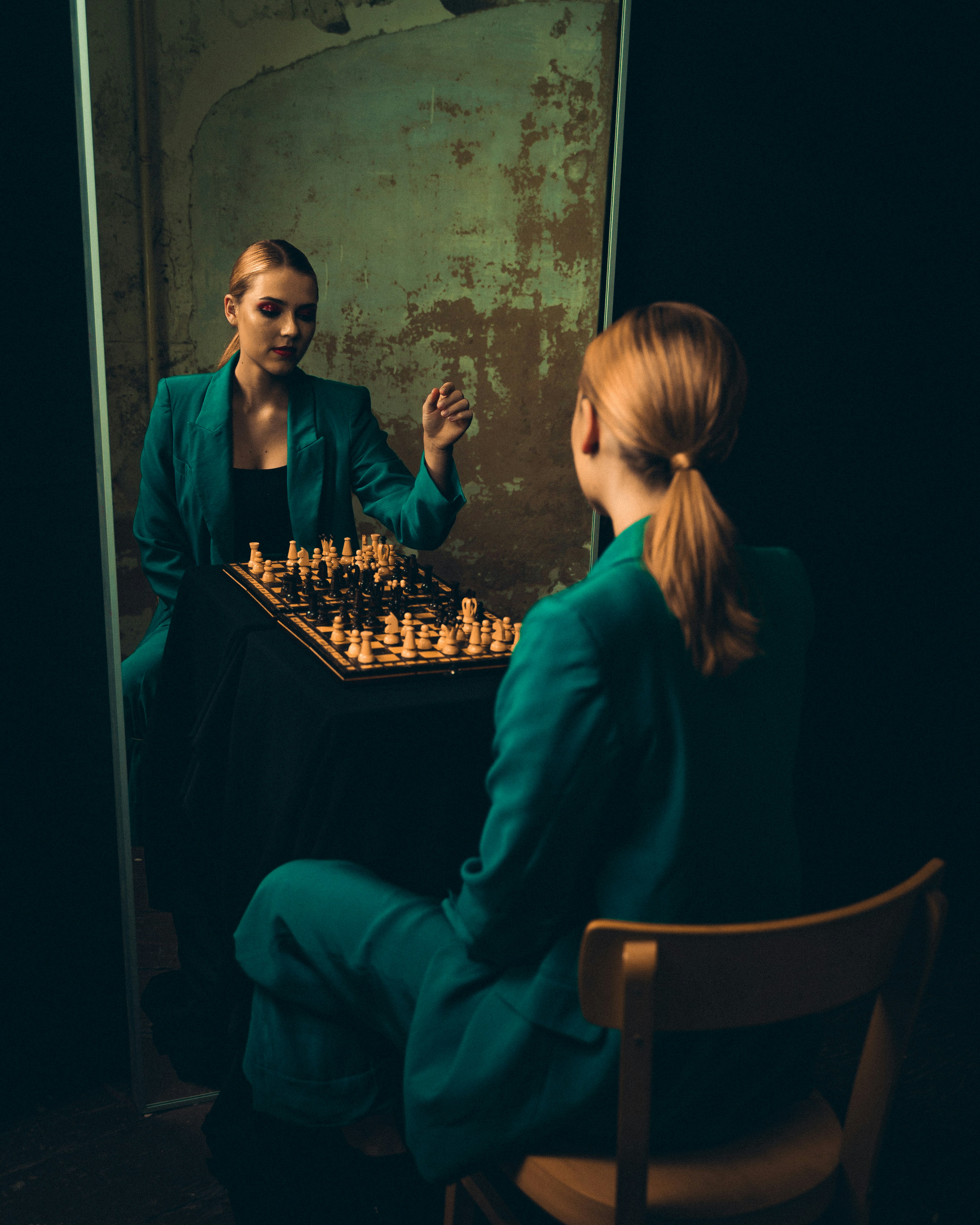 A woman plays chess chess in front of a mirror
