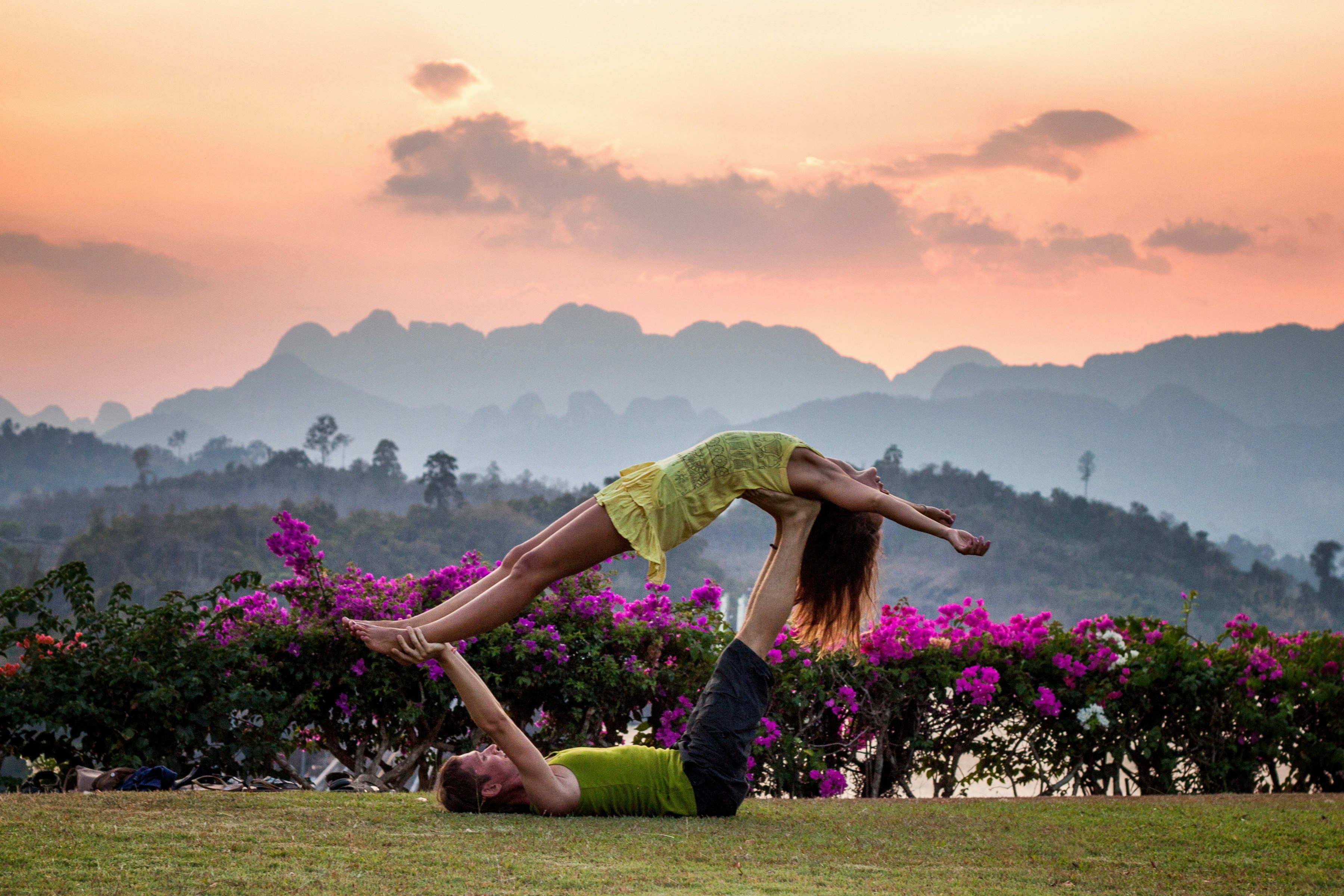 Man balaning a women upwardfacing on his feet. Pose is called high flying whale.