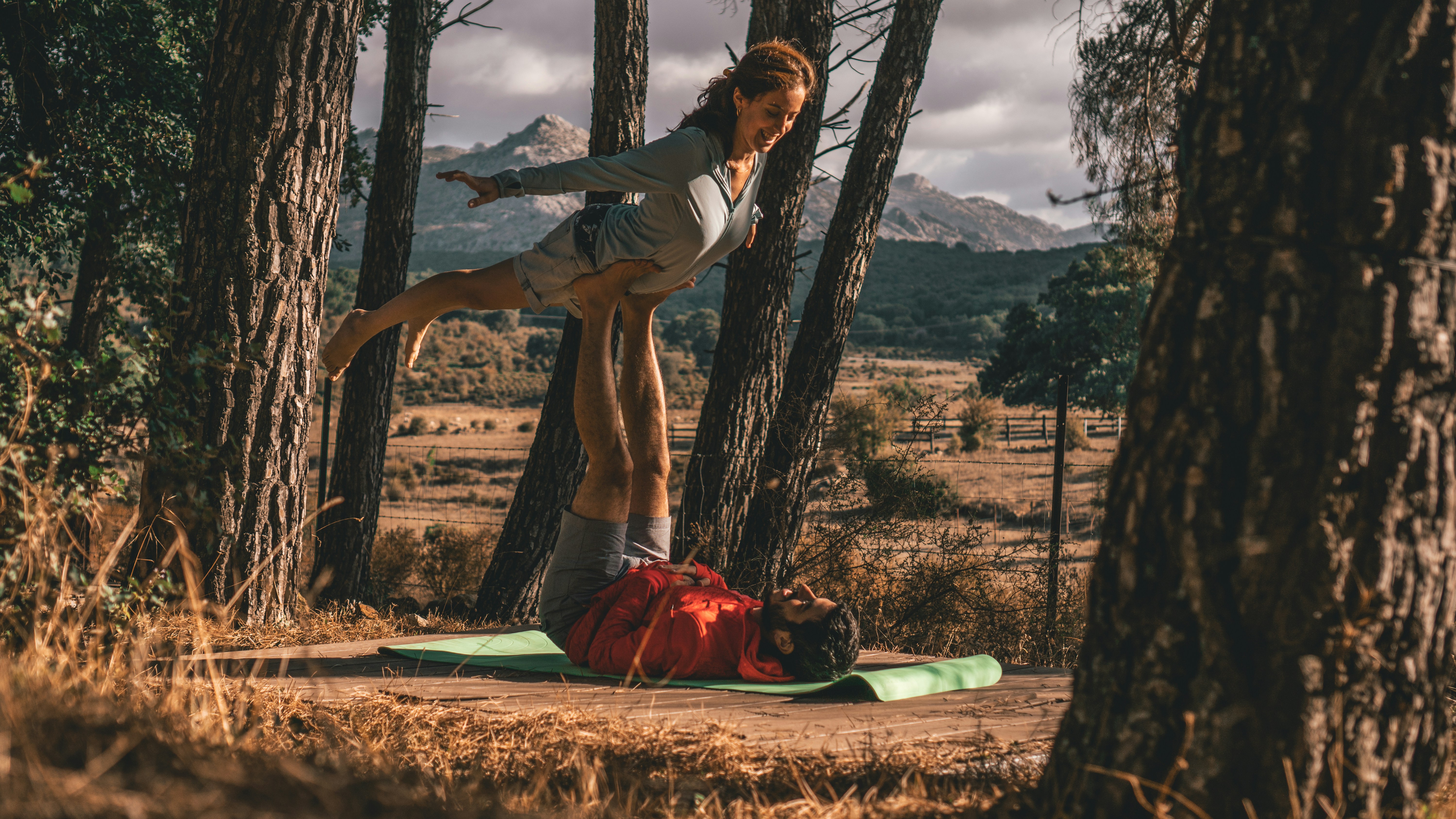 Man balancing women in the woods on his feet. Pose is called bird