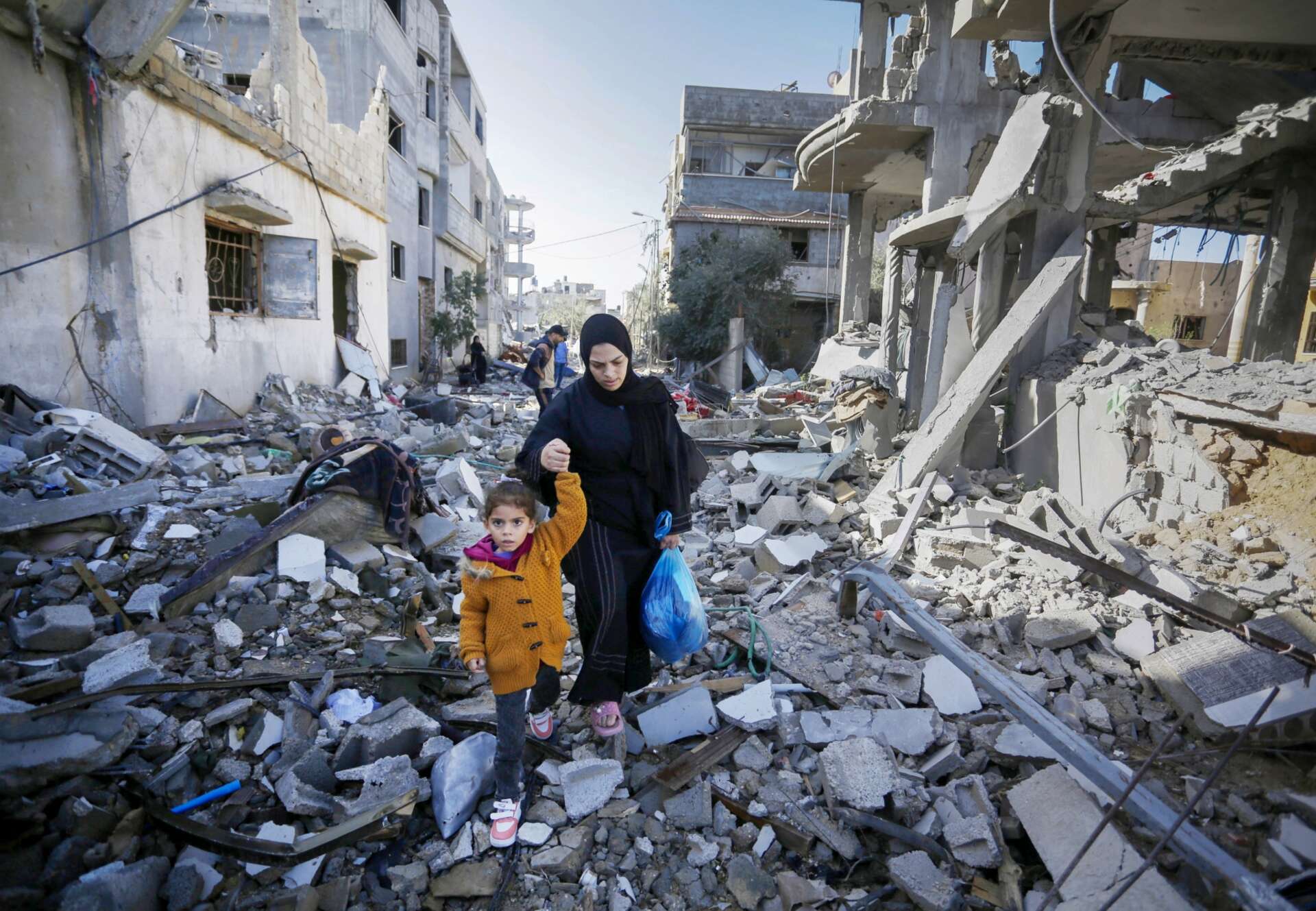 Displaced Palestinians walk through their destroyed neighborhood in Gaza during a temporary ceasefire to check on their homes and collect any items that remain intact.