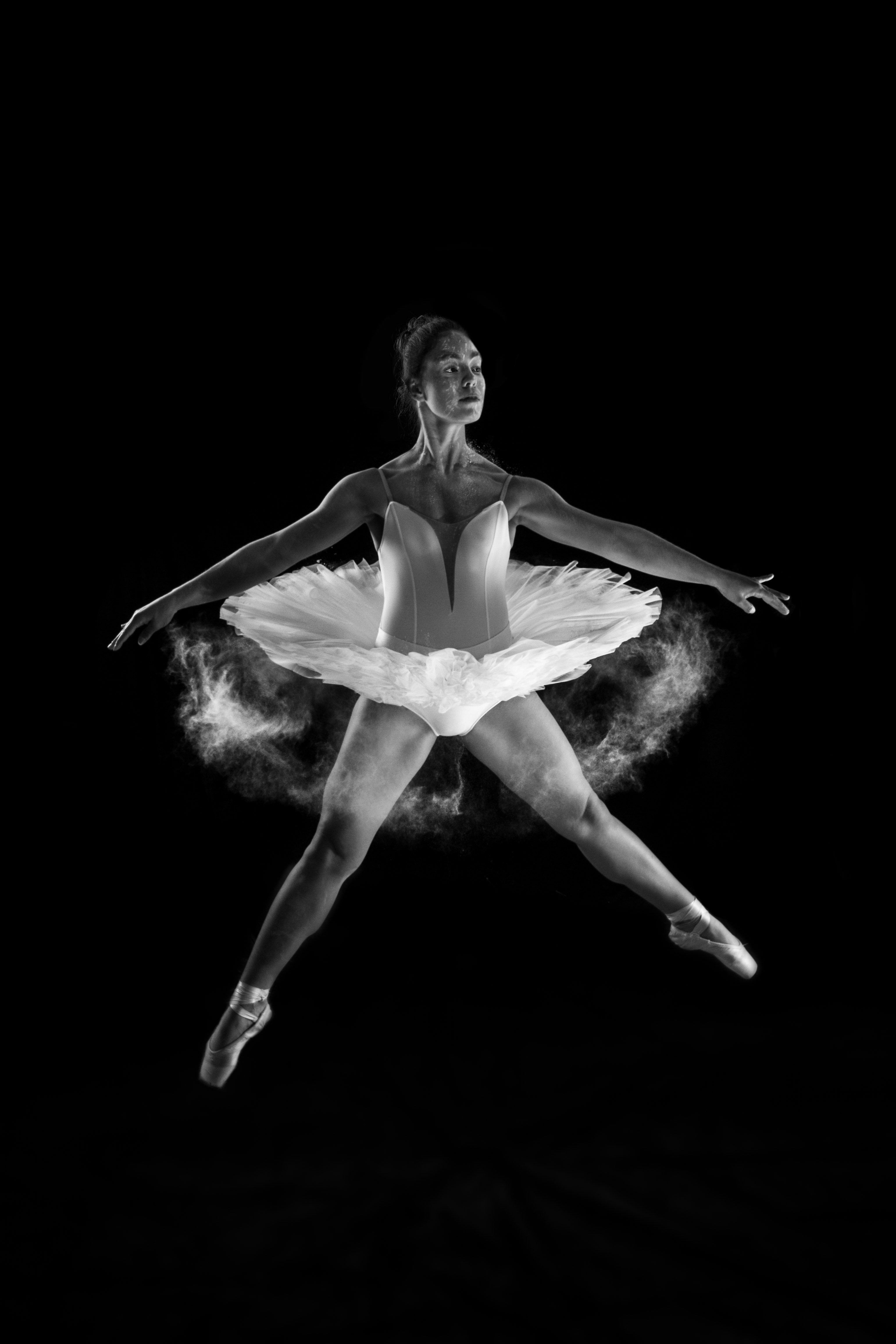 Black and white photo of a ballerina jumping a grand jeté