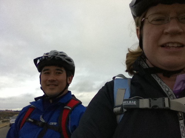 man and woman in bike helmets pausing along a bike path