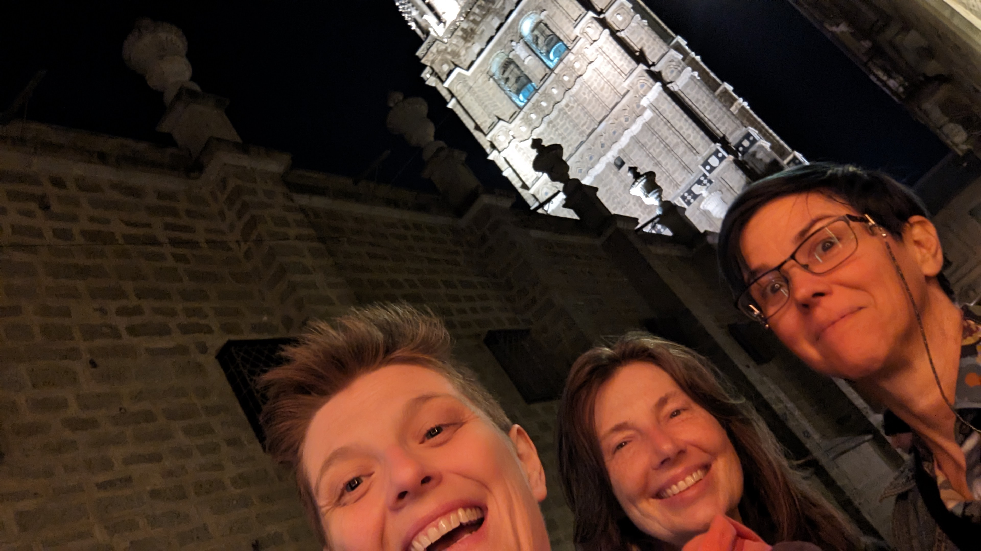 three women in front of a church at night