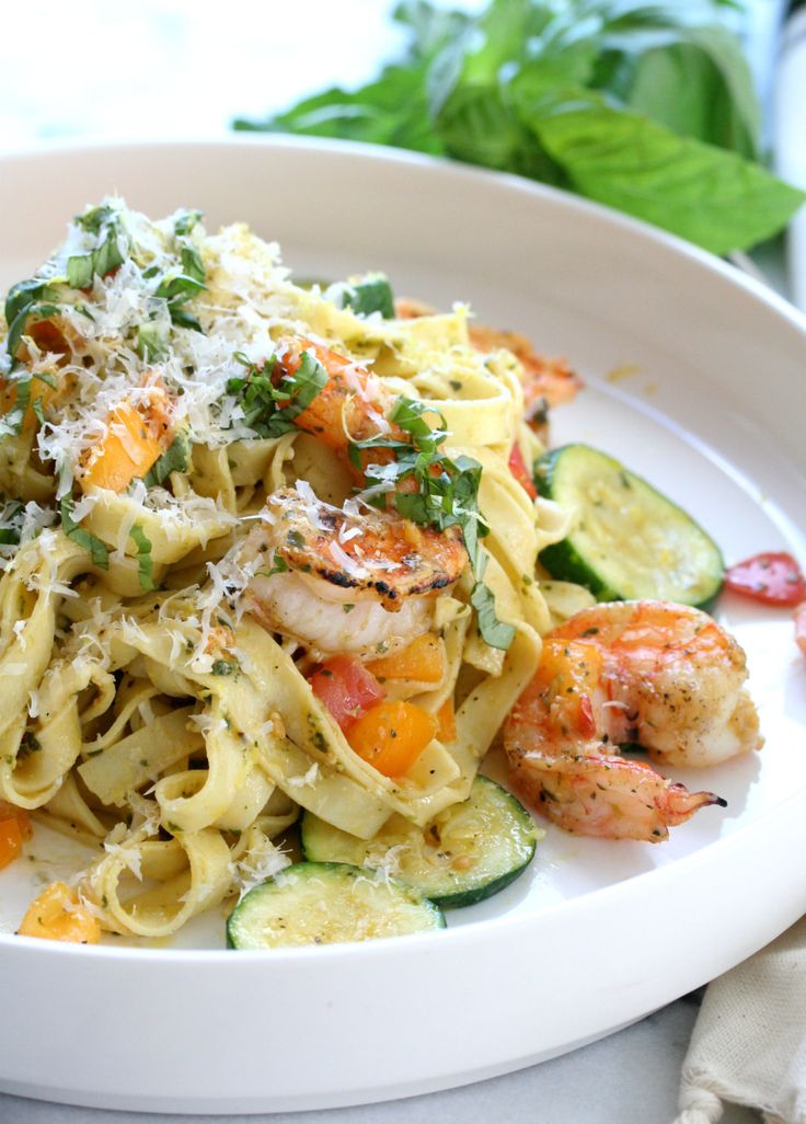 Primavera tagliatelle pasta with shrimp, zuccini, peppers and tomato topped with parmesan