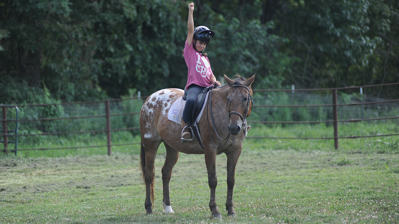 kid on horse doing fist pump in the air
