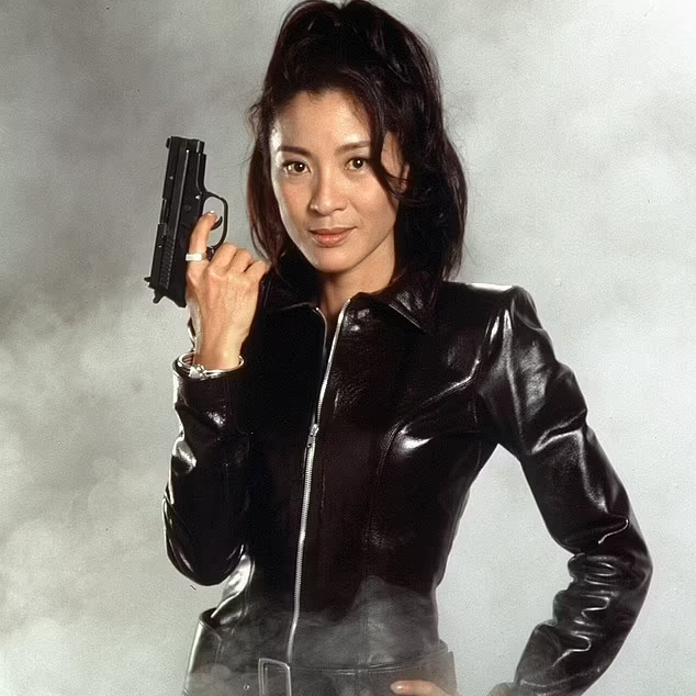 Michelle Yeoh as Wai Lin holding a gun and wearing a shiny, black zip-up outfit not entirely dissimilar to that worn by Black Widow
