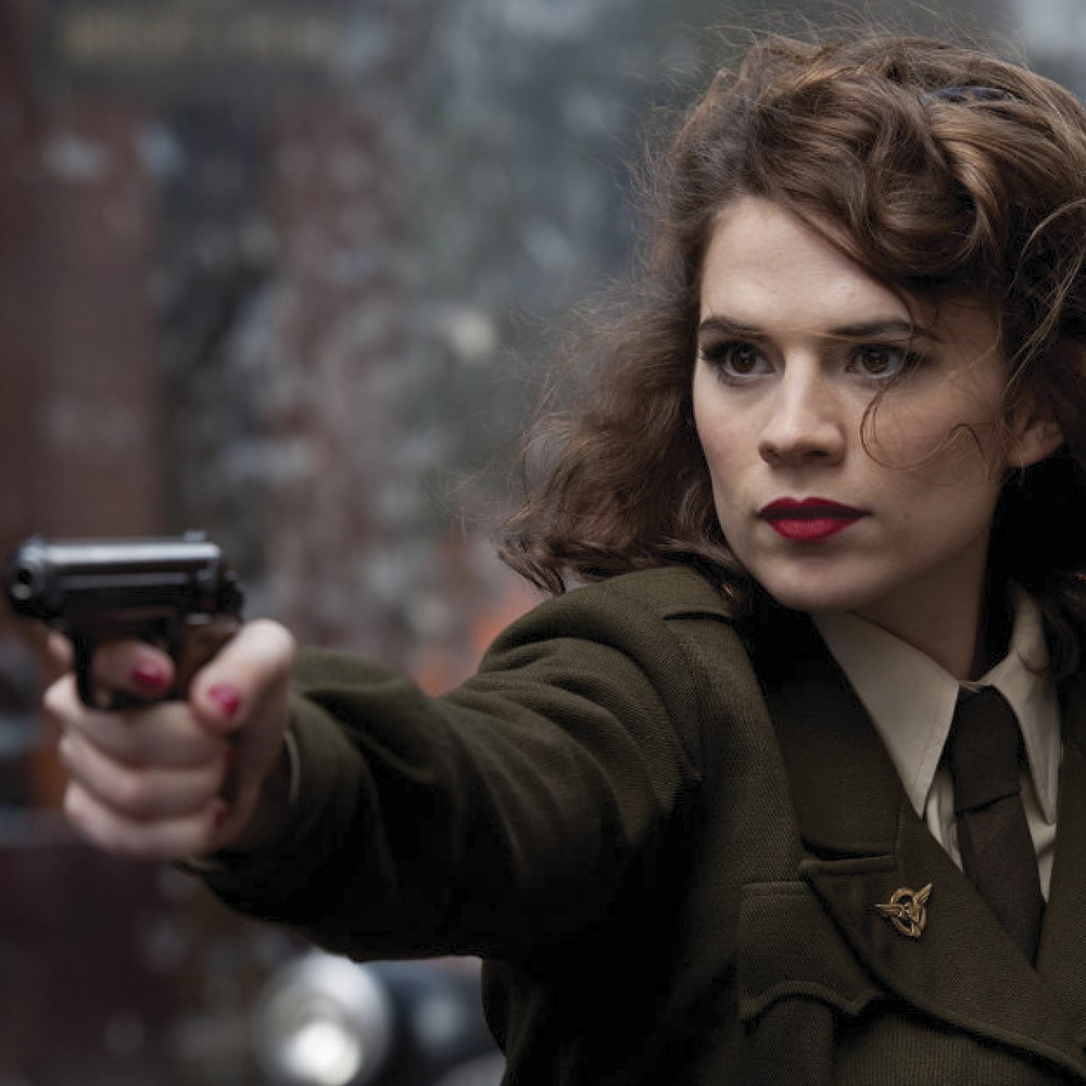 Hayley Atwell as Peggy Carter, in an army uniform with a gun