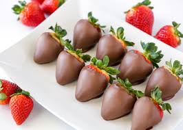 Strawberries dipped in chocolate, on a plate.