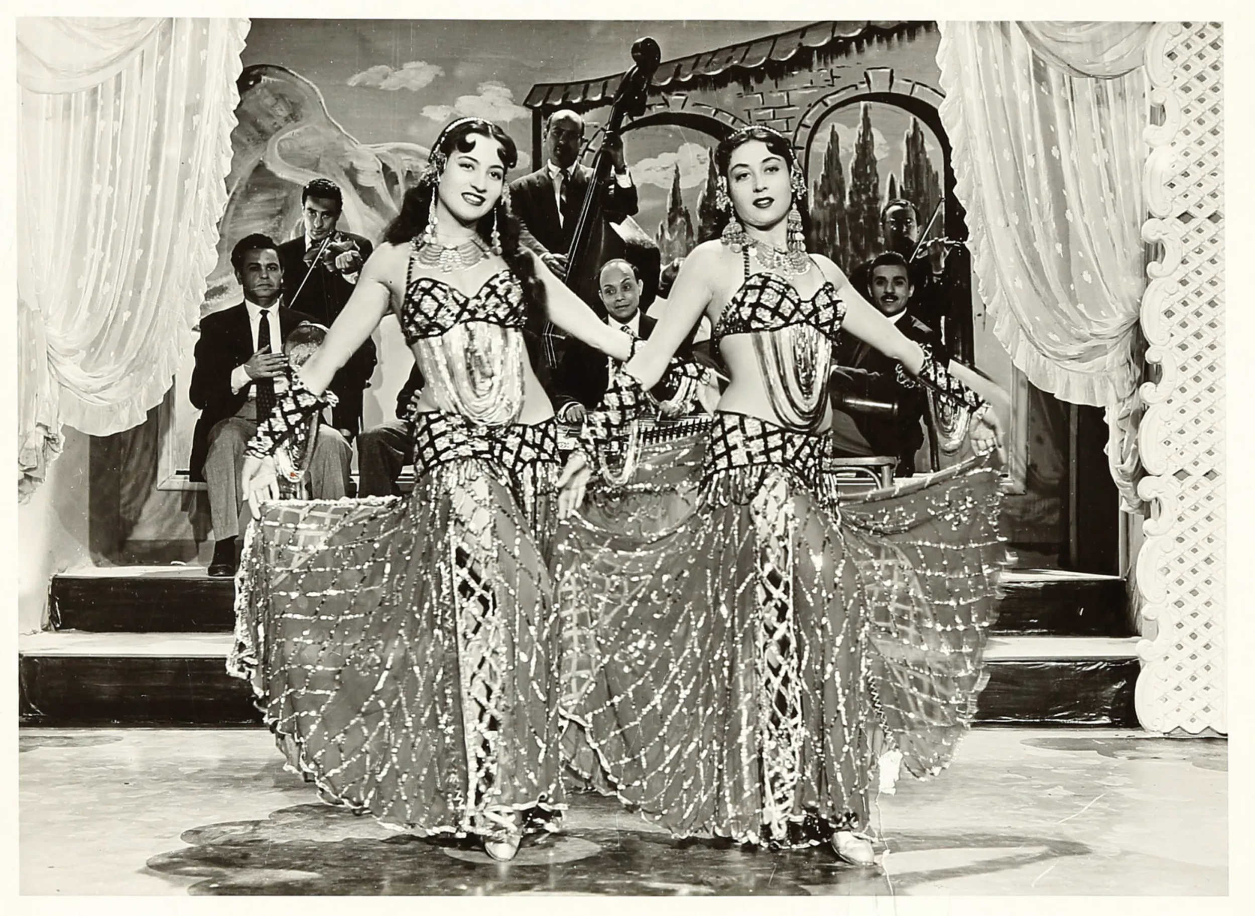 vintage phototograph of two belly dancers dressed in the same outfit on stage