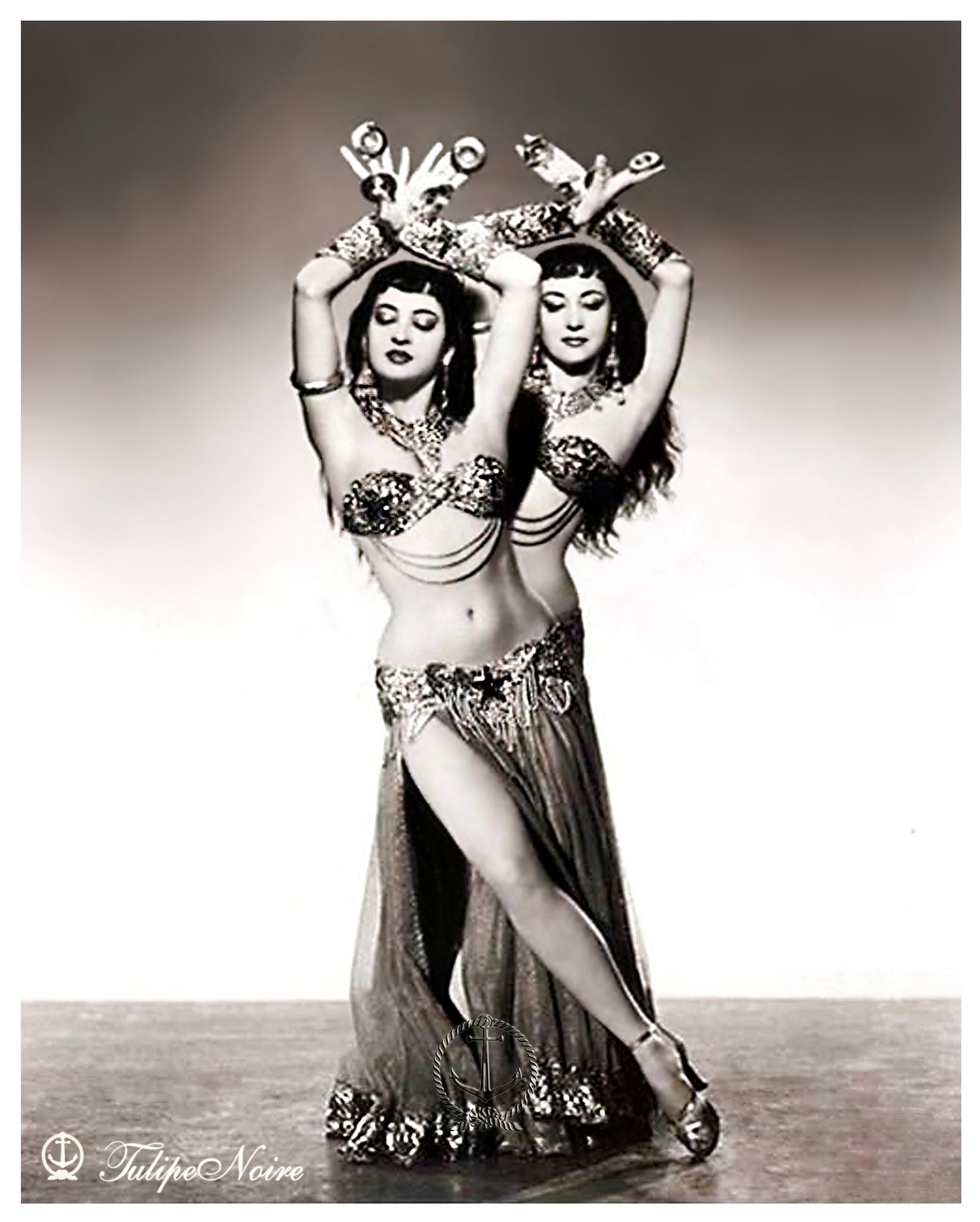 vintage photograph of two bellydancers with arms raised