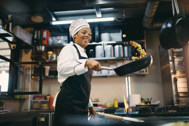 Chef tossing food in hot pan over stove