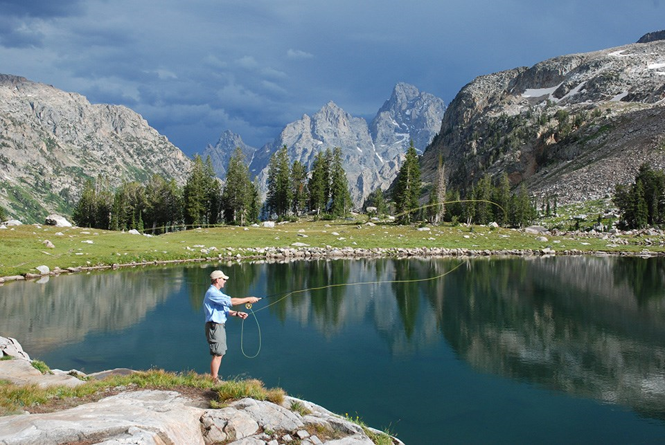 man fishing with mtns in background