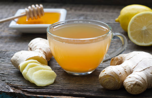 lemon, ginger and honey tea with a sliced lemon, sliced ginger root and honey in a bowl