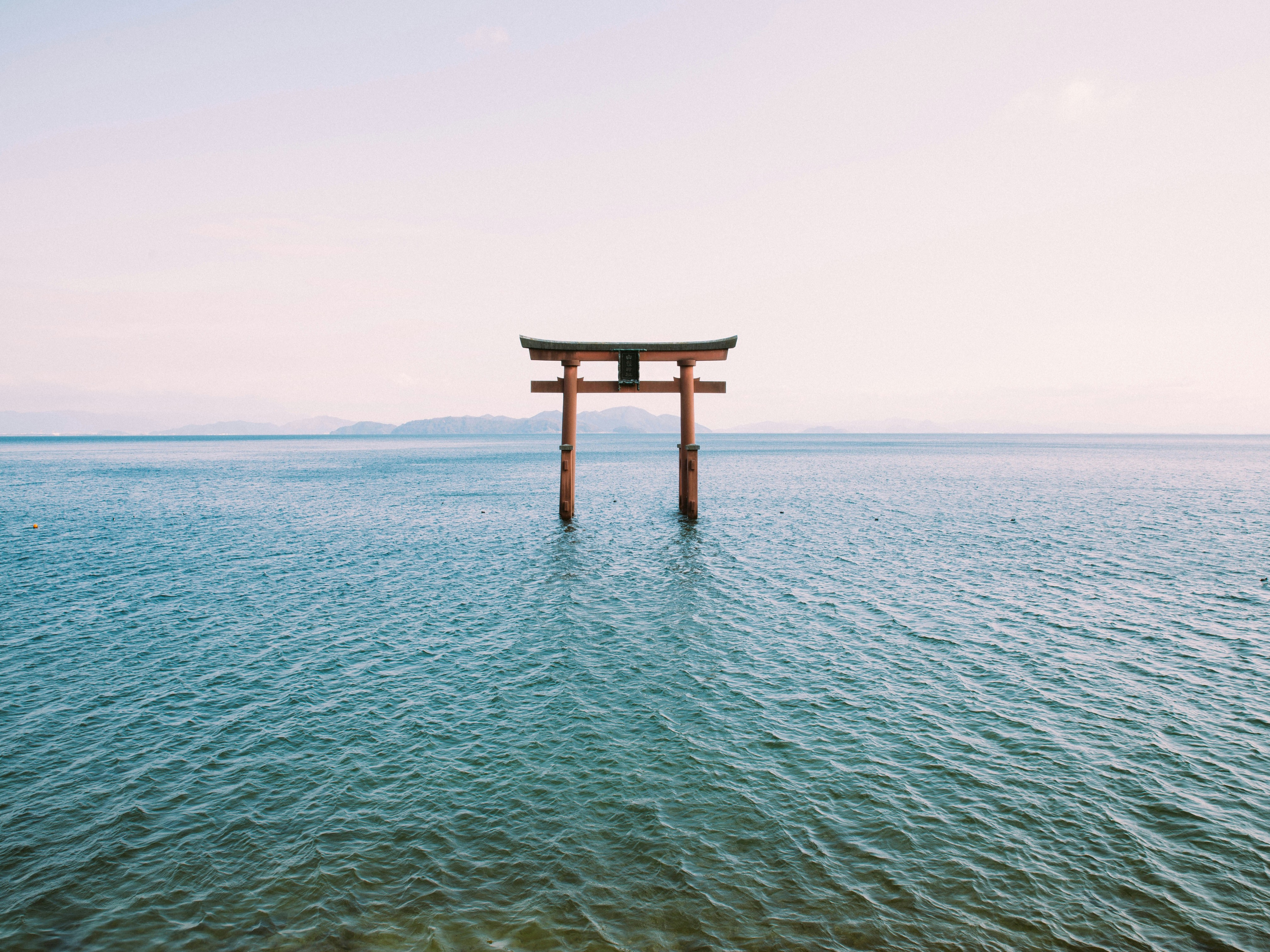 A red torii gate standing in the sea, symbolizing the transition to a sacred space.