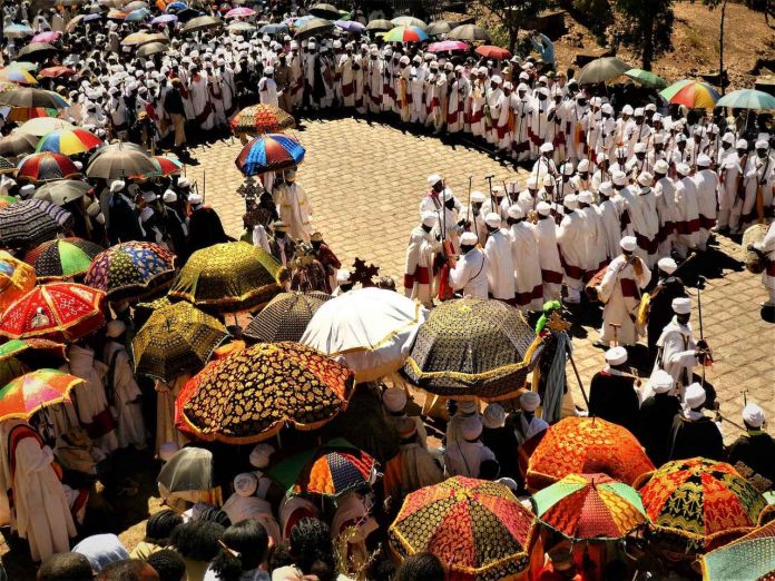 Clergy holding decorated crosses during outdoor Timket ritual