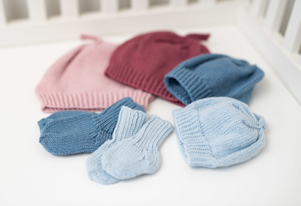 Knitted hats and socks on soft surface. Knitted in pink,red, blue and light blue,  
