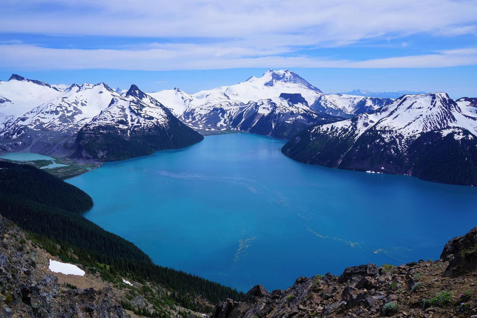 Blue-Garibaldi-glacial-lake-surrounded-by-snowpeaked-mountains