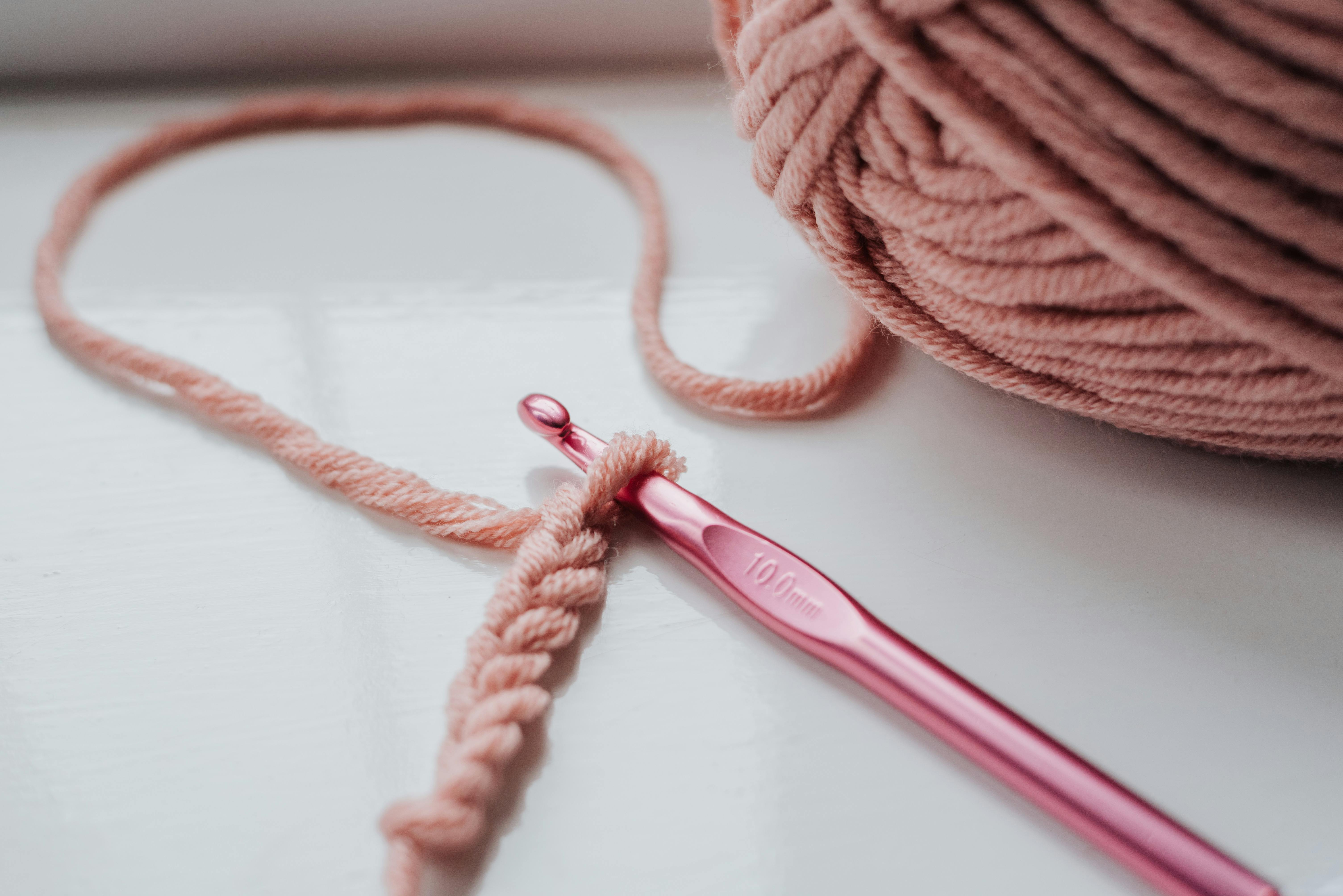 a crochet hook with a starting chain made of pink yarn