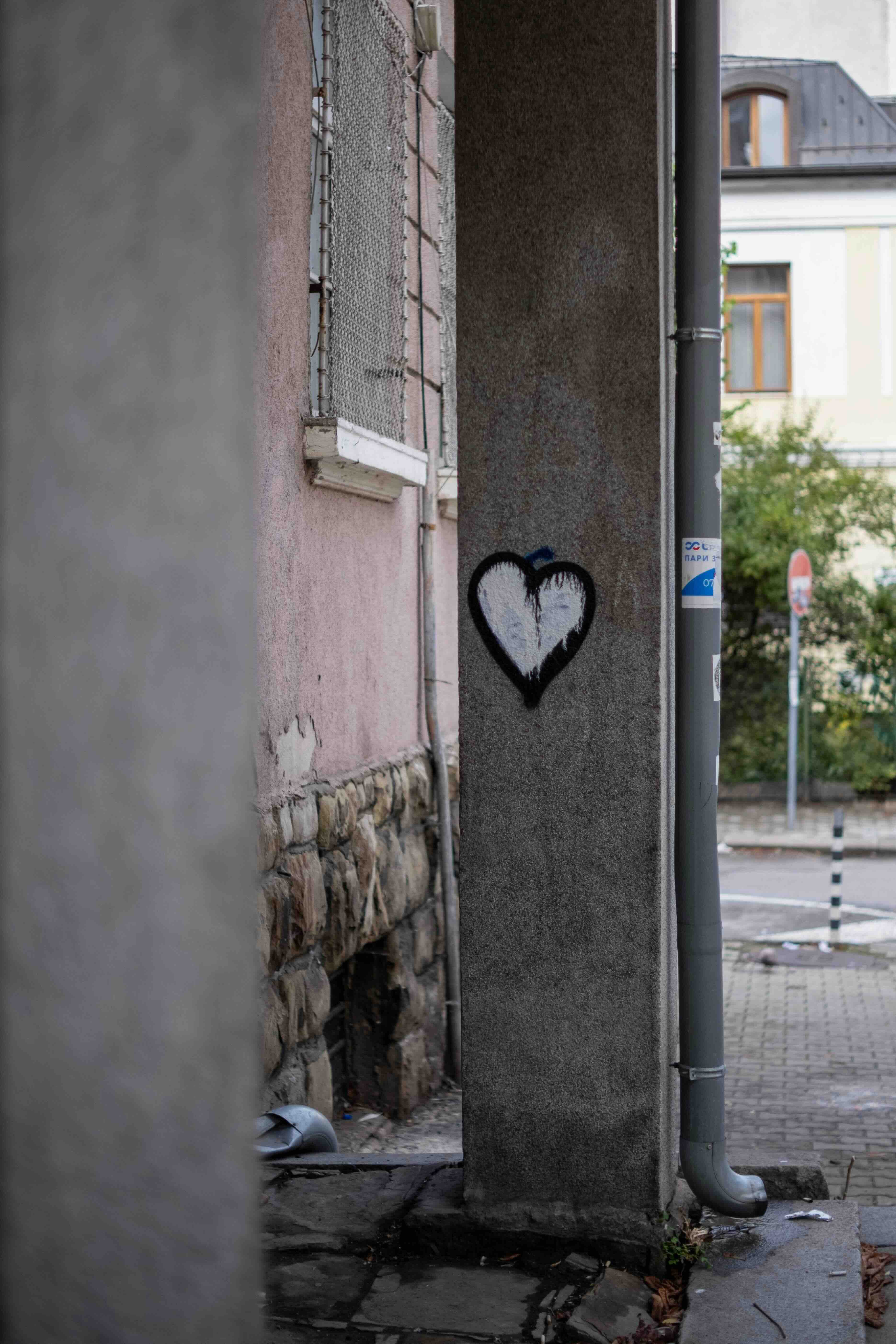 Graffiti heart painted on a concrete pillar in an empty street
