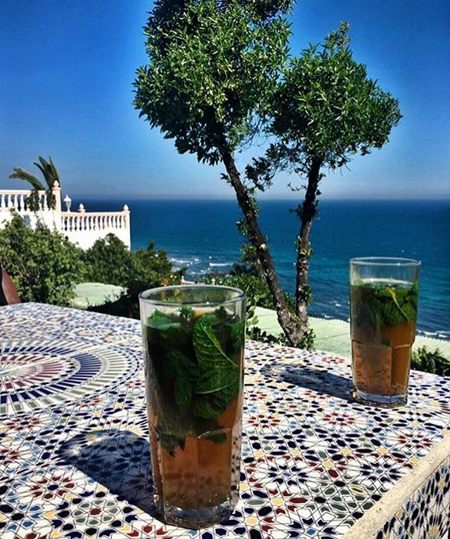 Moroccan mint tea on blue zellij tile with ocean view at Cafe Hafa in Tangier