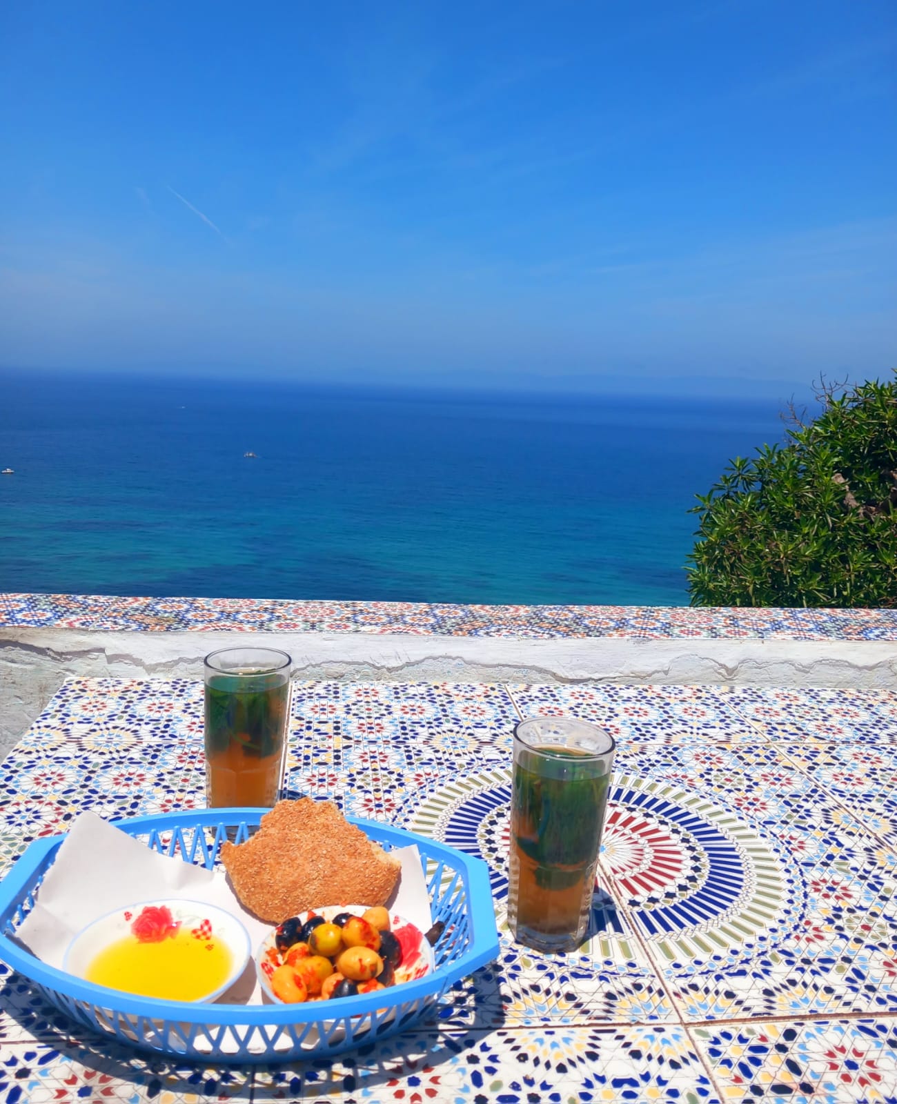 Moroccan mint tea on blue zellij tile with ocean view at Cafe Hafa in Tangier