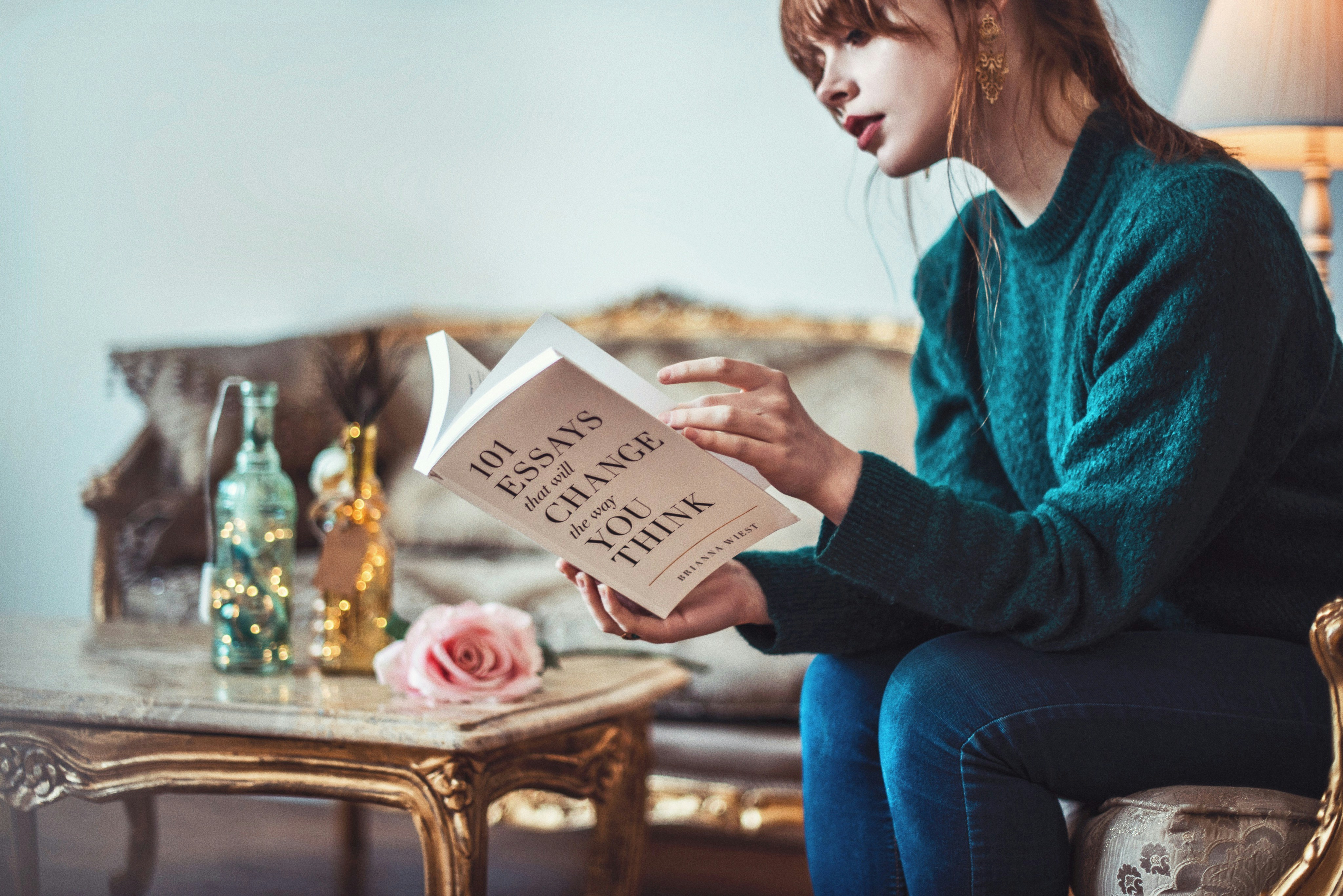 girl in green sweater reading book of essays